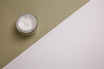 A jar of natural cream on a khaki background.