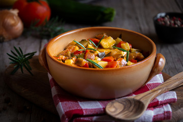 Chopped cooked vegetables on dark wood. Traditional ratatouille with zucchini, bell pepper and eggplant