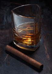 Single malt scotch whiskey in luxury crystal glasses with cuban cigar on wooden background