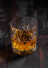 Single malt scotch whiskey in crystal glass on wooden background
