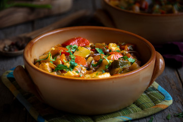 Chopped cooked vegetables on dark wood. Traditional ratatouille with zucchini, bell pepper and eggplant