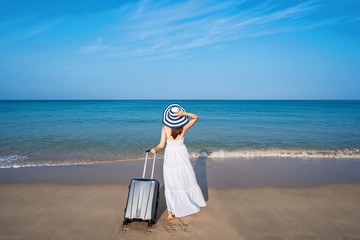 Young asian woman traveler with baggage at tropical sand beach, Summer vacation concept