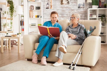 Fototapeta na wymiar Nurse woman reading a book on nursing home for ill senior woman.