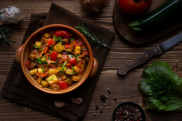 Chopped cooked vegetables on dark wood. Traditional ratatouille with zucchini, bell pepper and...