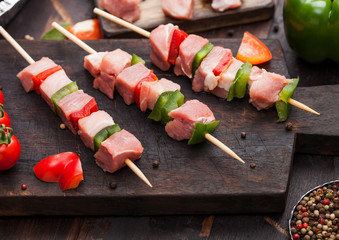 Raw pork and chicken kebab with paprika on chopping board with salt and pepper on wooden background.