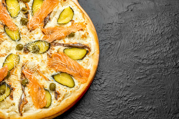 SAN MARINO pizza on a black background, cream-based with mozzarella, Parmesan, salmon, pickle and olives