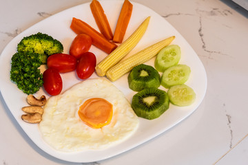 Fried eggs with vegetables in white plate  quick and easy breakfast