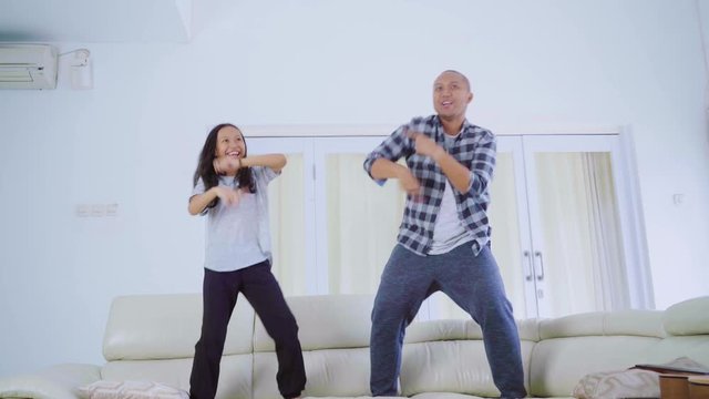 Father and child doing silly dance on couch