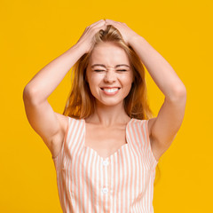 Funny Teen Girl Grimacing And Touching Her Hair Over Yellow Background