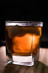 Glass of whiskey on wooden background close up