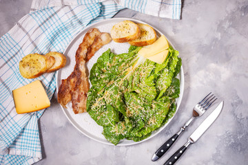 Caesar salad with crispy bread and bacon close up on concrete background