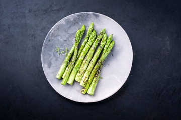 Traditionell gegrillter grüner Spargel mit Kräuter als Draufsicht auf einem Modern Design Teller...