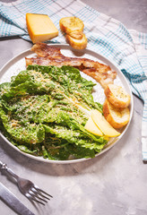 Caesar salad with crispy bread and bacon close up on concrete background