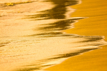 Water on the sandy shore at sunset.