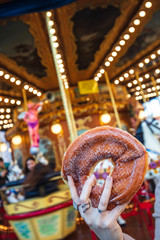 A sugary donut in front of an ancient German Horse Carousel built in 1896 in Navona Square, Rome, Italy