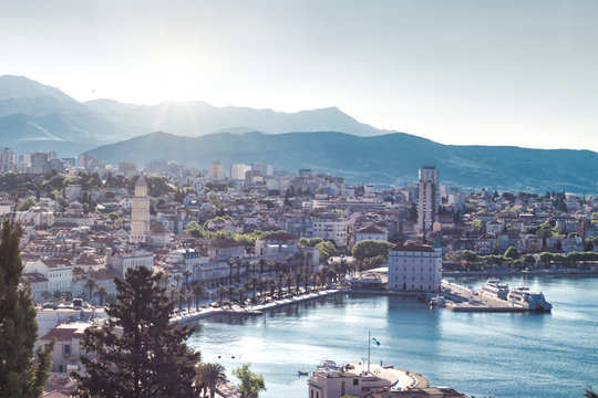 Town of Split, Croatia seen from the Marjan hill. Early morning sun peeking over the mountains on a cold day, distant mountains blurred in the fog.