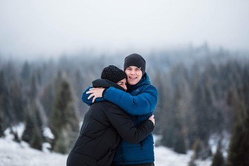 Beautiful couple in love. Portrait of winter background. The guy and the girl have a rest in the winter woods. Young couple walking in winter park. Girl in the arms of a guy looking at each other.