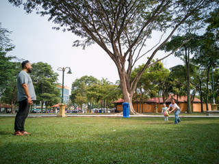 Naklejka premium Family of three playing ball in the Malaysia park.