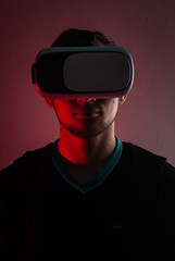 A hacker in the VR glasses in red light, the gamer in the virtual space,