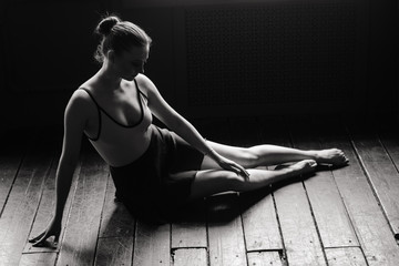 Beautiful young female classical ballet dancer on pointe shoes wearing a black leotard and skirt on...