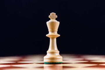 white chess king on a chessboard on a black background
