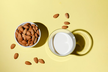 Almond milk in a glass on yellow background