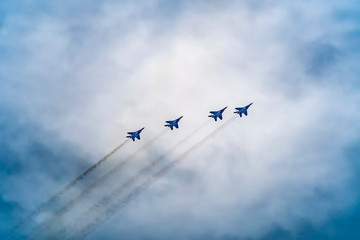 Military fighter aircraft flying in a simple construction against a background of white sky and clouds