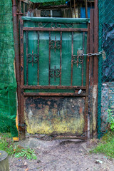 Old wrought iron gate of a house. Rusty and damaged door that leads to private property. Oxidation due to bad weather.