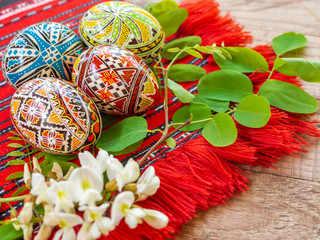 nicely hand decorated romanian orthodox easter eggs with traditional motifs on a red cloth with acacia flowers aside