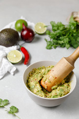 Mexican sauce guacamole in a mortar with ingredients