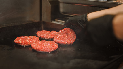 Tasty Close Up Shot of a Meat Patty Being Prepared on a Griller. Fresh Ground Beef is Grilled on a Hot Gas or Electric Grill. Cook is Seasoning a Patty for Burger from Fresh Minced Meat with Salt.
