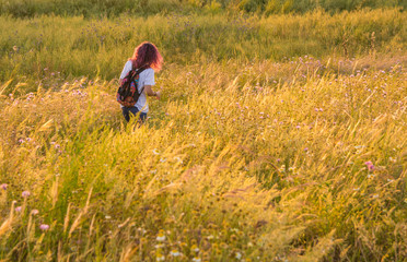 Naklejka na ściany i meble Adventurous Woman, Walking With Her Backpack Through The Fields Of Extremadura, Spain. Beautiful Natural Landscape In Extremadura With Its Colors And Wild Flowers. Lifestyle.