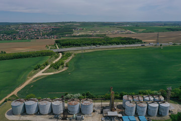 Fototapeta na wymiar Aerial view with drone, agricultural silo, next to wheat or barley field - industrial elevator dryers, building exterior, storage and drying of cereals, wheat, corn, soybeans, sunflowers. In Europe