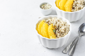 Vegan breakfast, coconut oatmeal porridge with oranges and seeds. Selective focus, copy space.