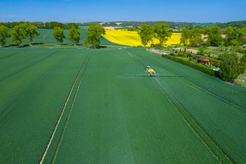 Green Fields. Aerial view of the tractor spraying the chemicals on the large green field....