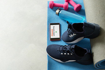 Fitness equipment and smartphone on gray floor background. Training indoors.