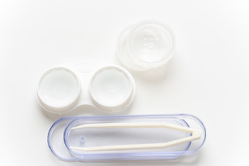 Contact lenses are in a solution in a container for contact lenses and tweezers in a case against a light background. Contact lenses for correcting vision.