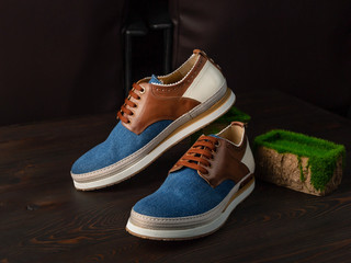 Men's sneakers made of denim and genuine leather on a dark wooden background