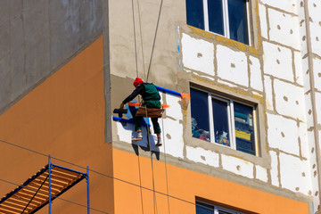 Fototapeta na wymiar Styrofoam insulation of high-rise building. Rope access working. Concept of industrial alpinism