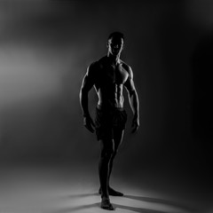 Fototapeta na wymiar Strong Athletic Man - Fitness Model showing his perfect back isolated on dark background with copyspace