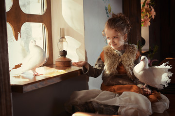 a girl in a medieval image sits by the window with doves and feeds them