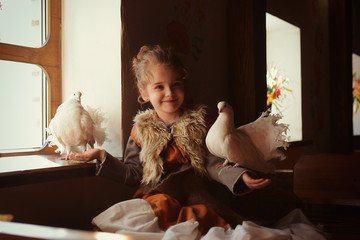 a girl in a medieval image sits by the window with doves and feeds them