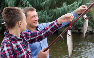 Happy father with son looking at fish on hook