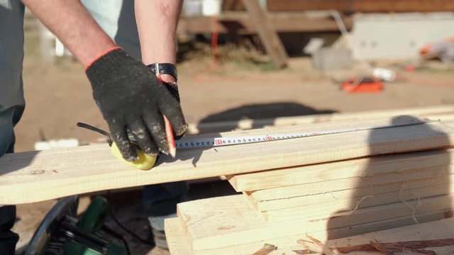 View from above. Carpenter with the pencil and the carpenter's square drawing the cutting line on a wooden board. Construction industry, do it yourself. Wooden work table.