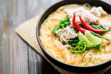Spicy rice noodles soup with spices and herbs (Thai Tom Yum) in a bowl, Asian food	
