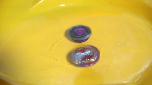 Collective image of the children's popular toy Beyblade. The battle of two Beyblade in the arena in a flat style.Slow motion.