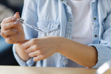 Young female blogger recording a tutorial video for her beauty blog about cosmetics.Vlogger testing hyaluronic acid serum,broadcast live video to social network at home. Blogging, skincare concept.