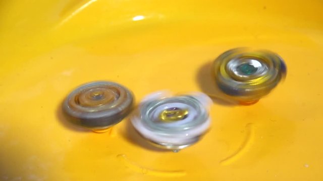 Collective image of the children's popular toy Beyblade. The battle of two Beyblade in the arena in a flat style.Slow motion.