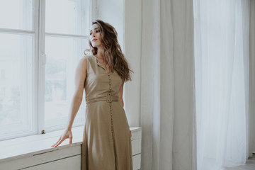 Portrait of a beautiful fashionable woman dressed in a dress of bed tones