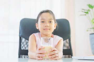 Cheerful little girl smiling and holding glasses of milk, Learn from home concept